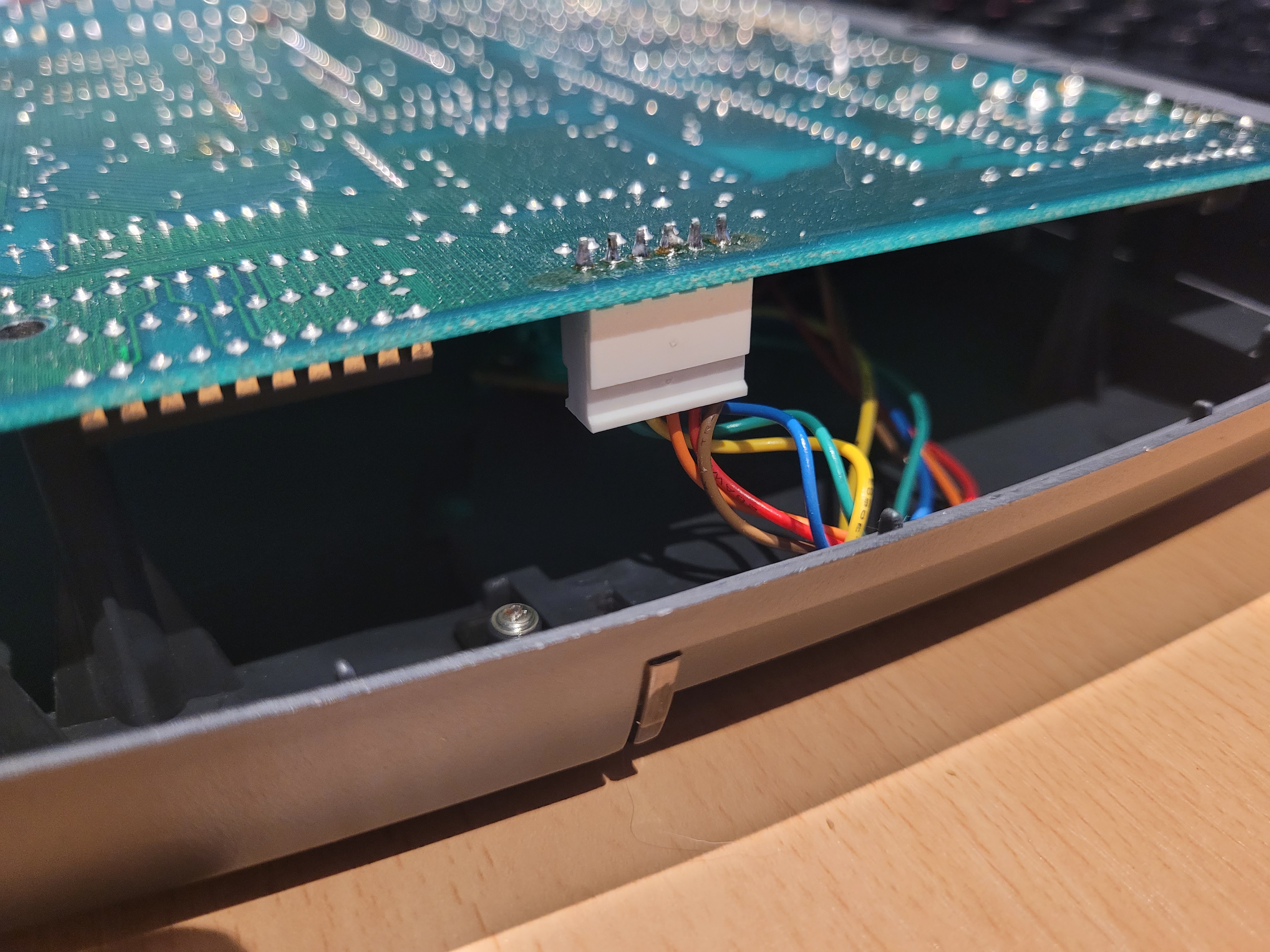 The white LED connector on the main PCB with coloured wires visible, photographed with PCB partially lifted